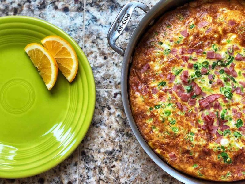 A pan of frittata, next to an orange slice