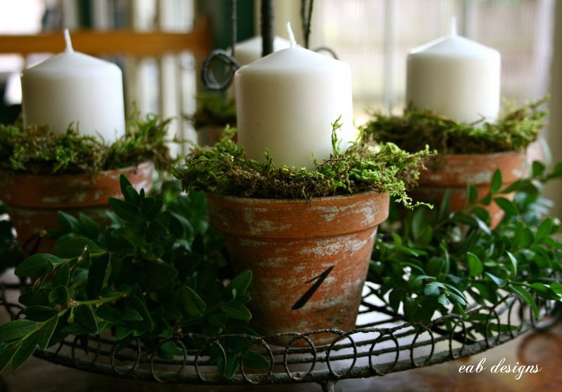 uma coroa de Advento com velas colocadas em vasos cerâmicos