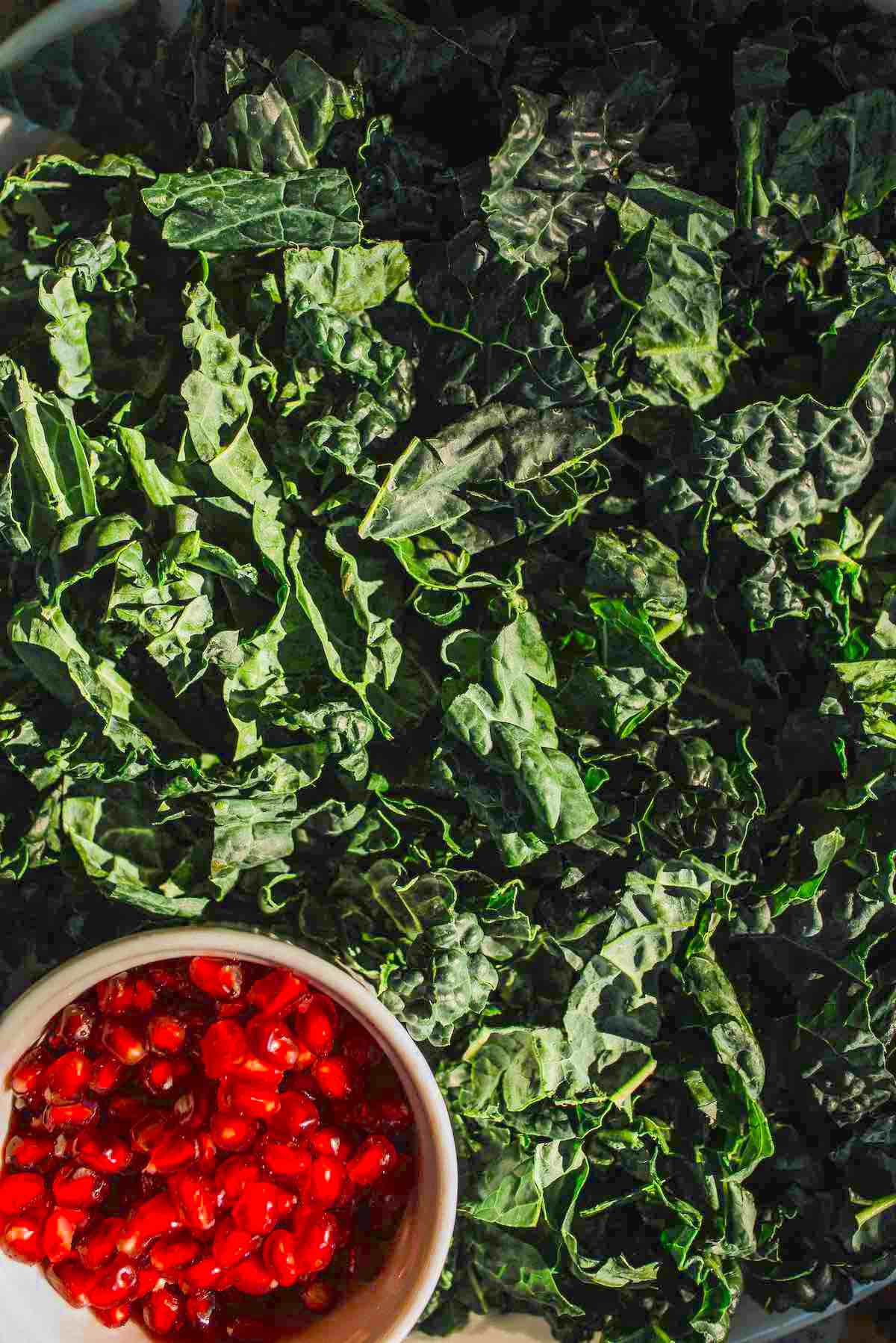 Kale winter greens with a container of pomegranate seeds