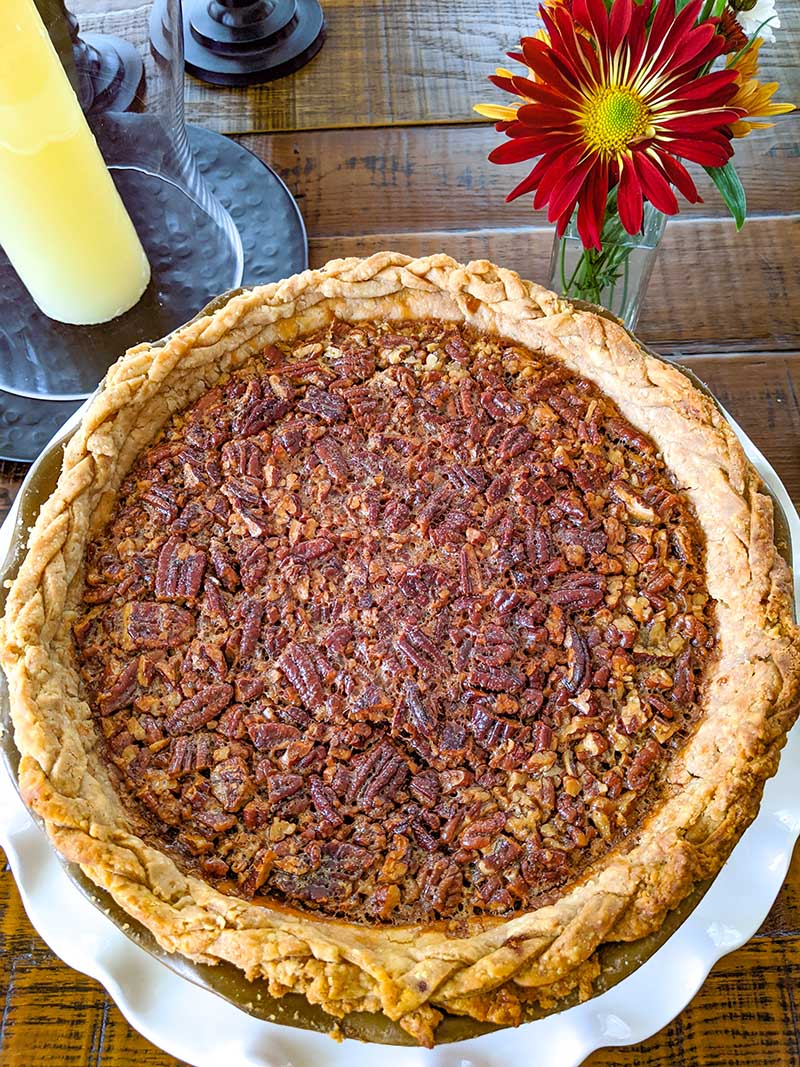 The finished Pecan Pie on a wooden table next to a red flower