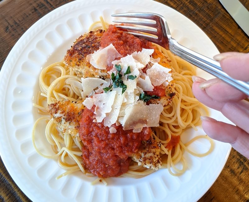 The finished Weight Watchers Chicken Parmesan on a plate, with a fork held above it.