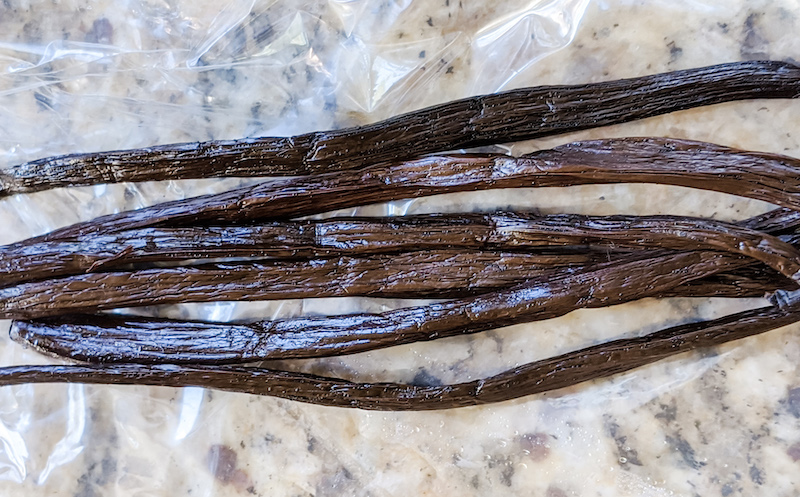 Six strings of vanilla beans sitting on a counter