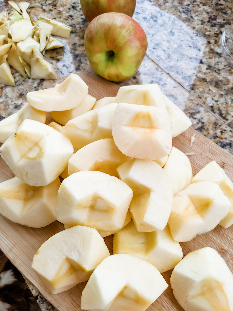 Chopped and skinned apples sitting on top of a wooden cutting board