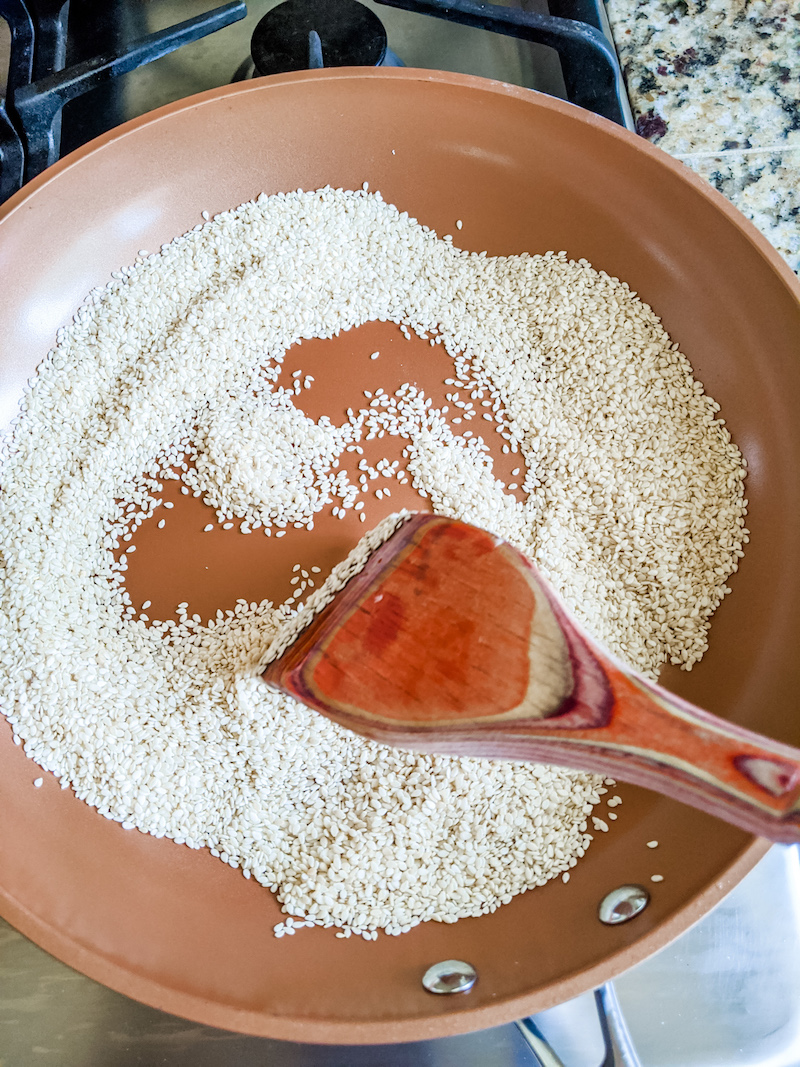 A skillet toasting some sesame seeds with a spatula