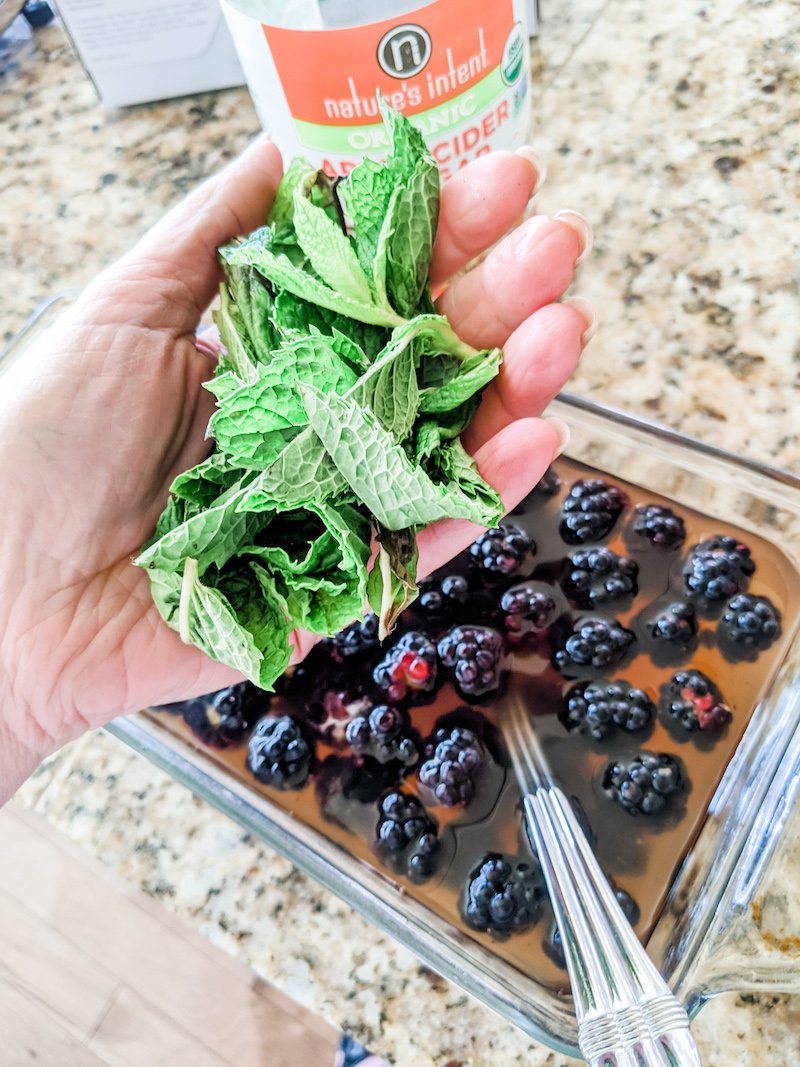 Fresh mint being added to the fruit and vinegar mixture