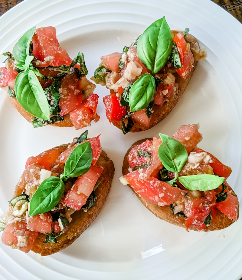 Four finished pieces of my easy tomato bruschetta sitting on a plate