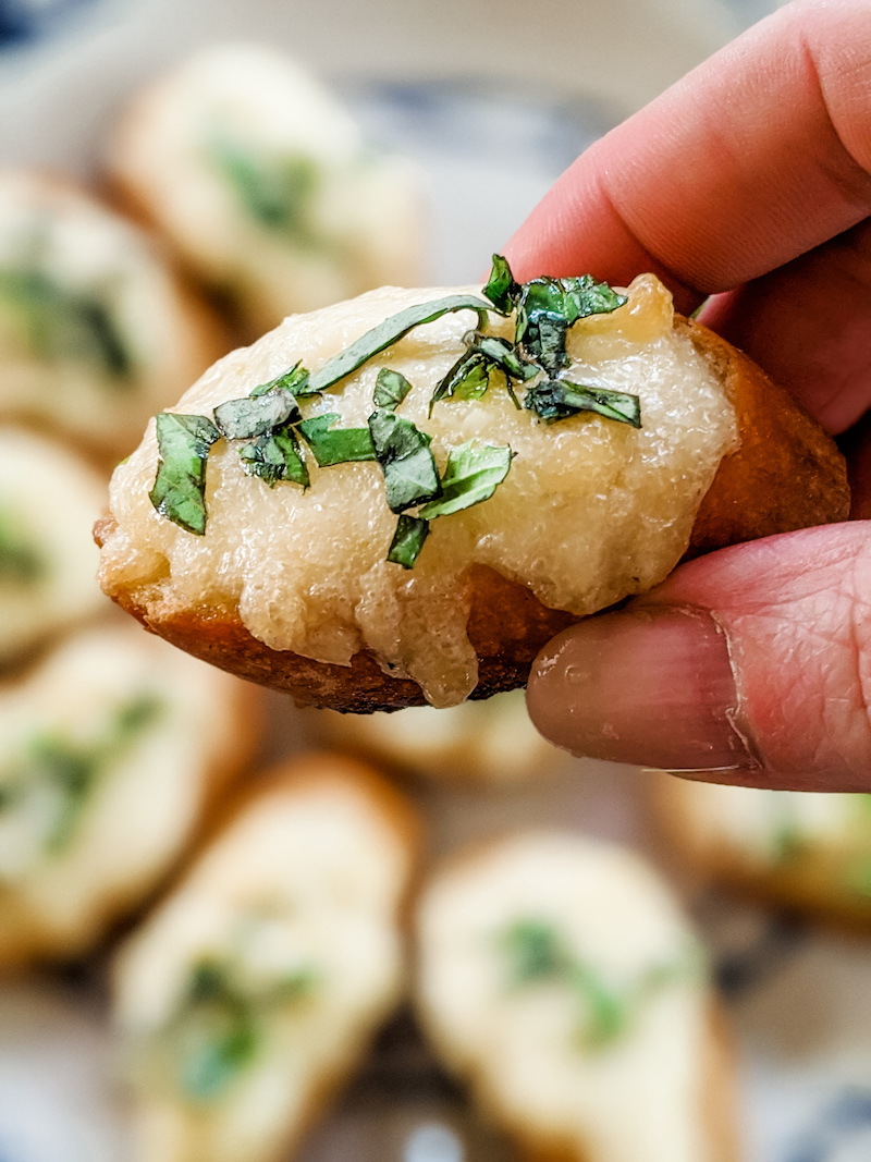 Marie holding the 3 ingredient appetizer, easy parm bread above a plate