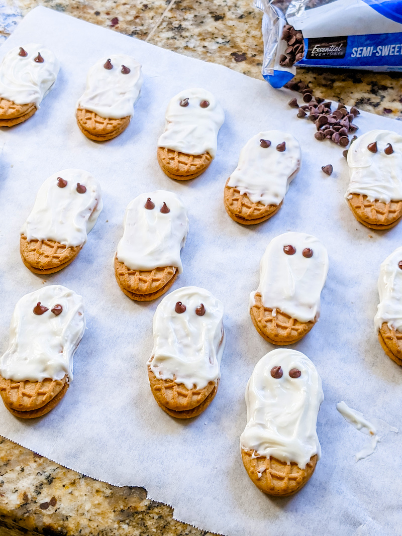 Several Easy Nutter Butter Ghosts resting on parchment paper after being assembled.