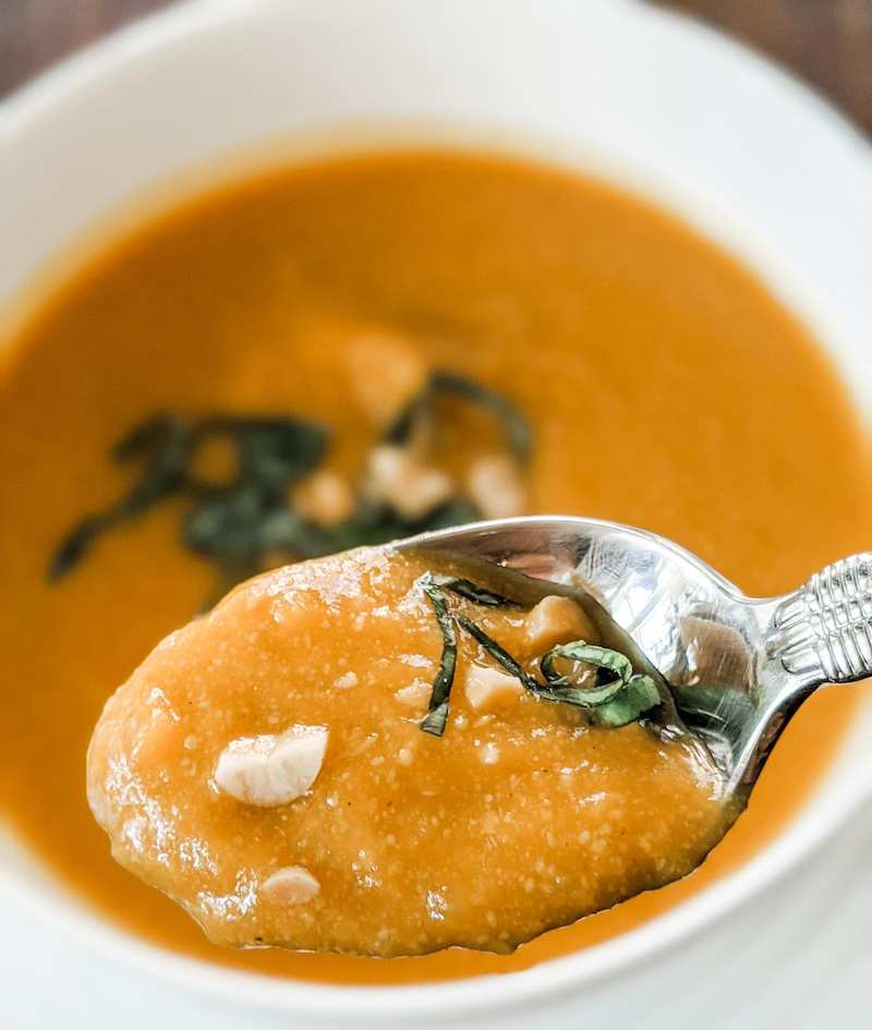 The finished slow cooker Thai Butternut Squash Soup, with a spoon picking up a bite.