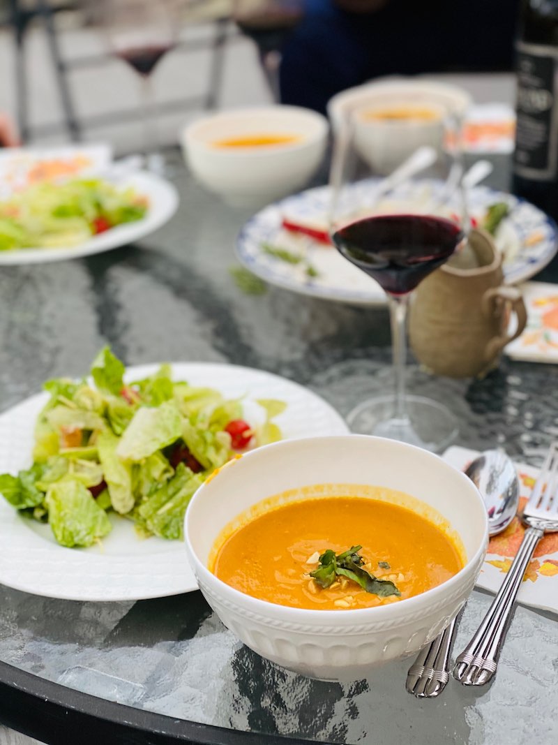 The finished Slow Cooker Thai Butternut Squash Soup on a table accompanied by wine and a salad