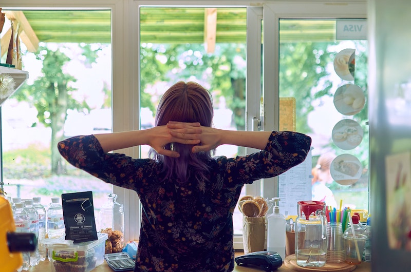 One of the things to do to stop worrying - unplugging. A woman in a dark shirt and her arms behind her head looking out her window