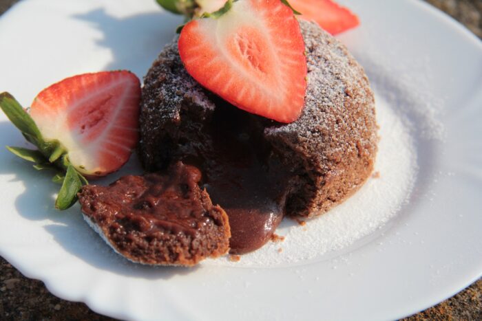 A piece of lava cake, sliced open an topped with strawberries