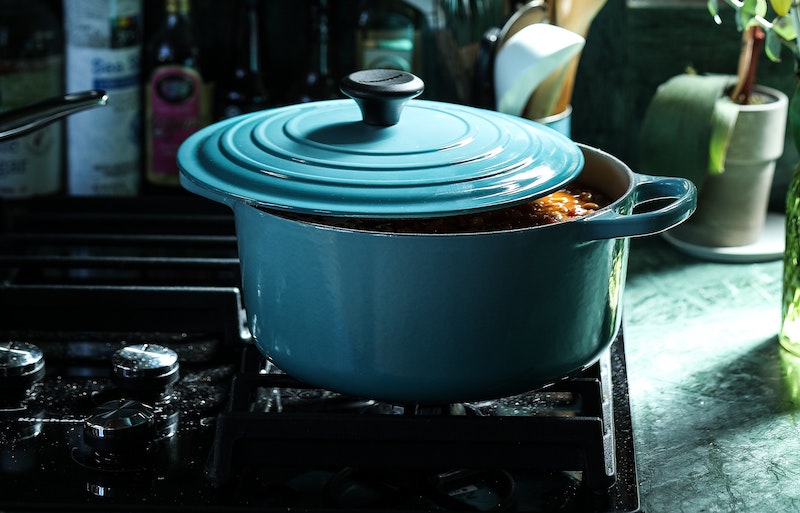 A photo of a crockpot with the lid slightly ajar on top of a stove top