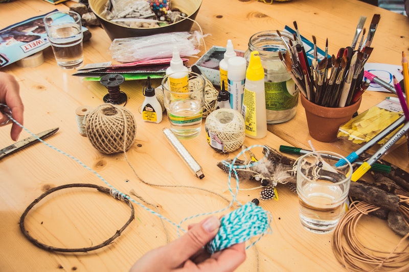 One of the things to do to stop worrying - a pair of hands above a table laden with crafting supplies (paints, brushes, yarn).