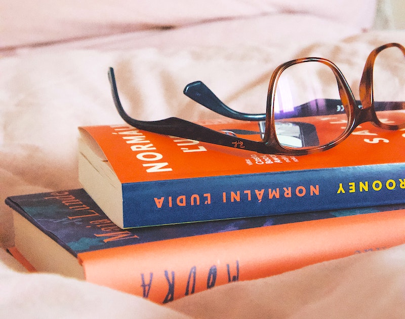 A stack of two books on a bed with glasses set upon them
