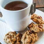 A cup of tea on a saucer surrounded by chewy pumpkin harvest cookies