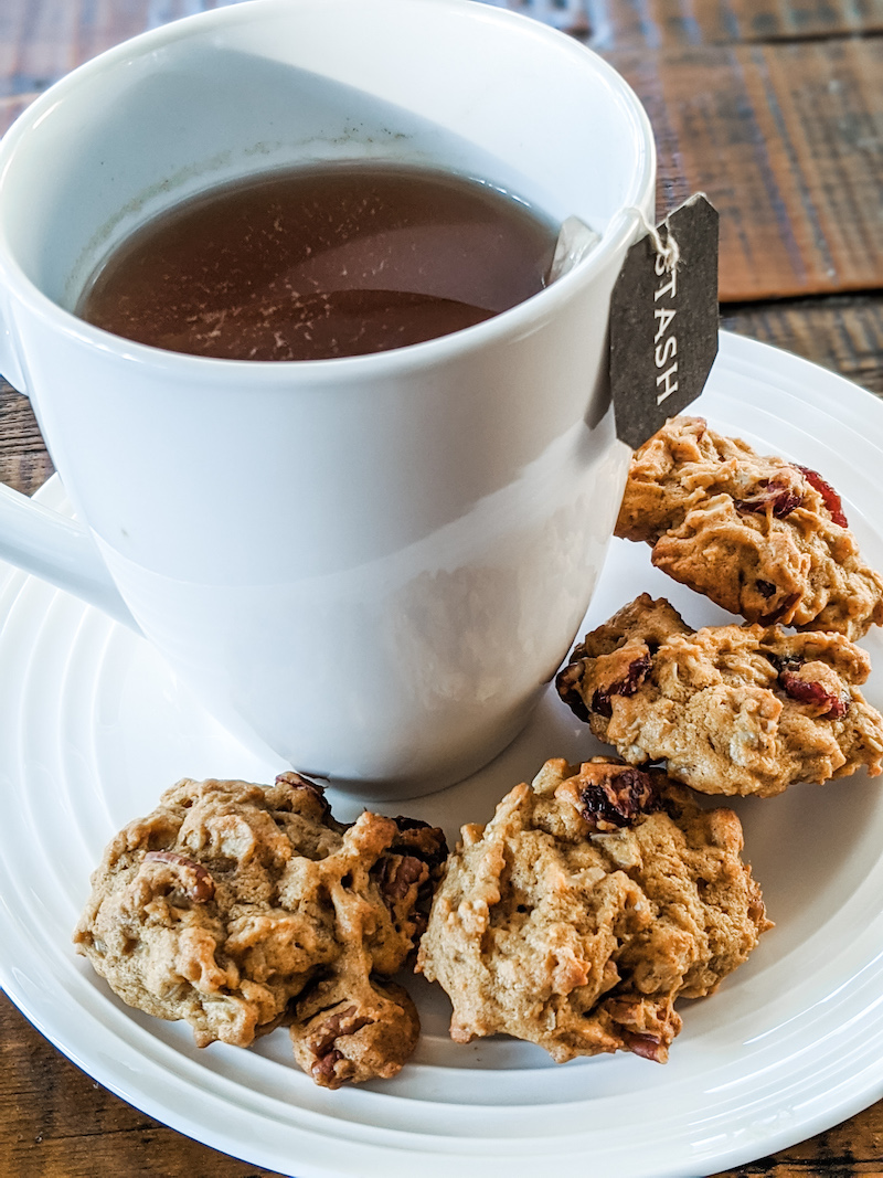 A cup of tea on a saucer surrounded by chewy pumpkin harvest cookies