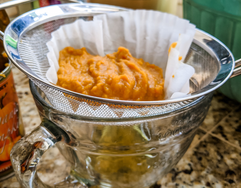 The pumpkin in a coffee filter, overtop a strainer to remove water