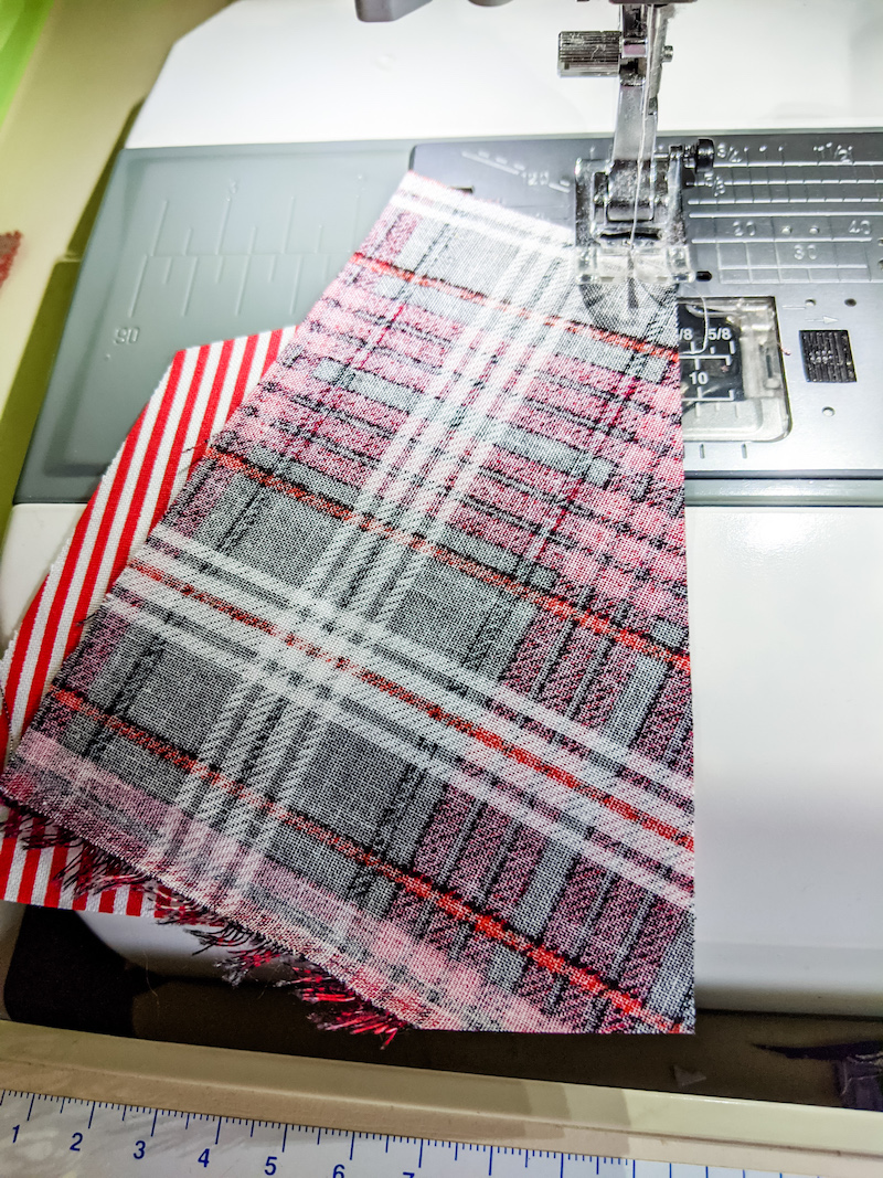 A straight line being sewn across the scraps of fabric on a sewing machine.