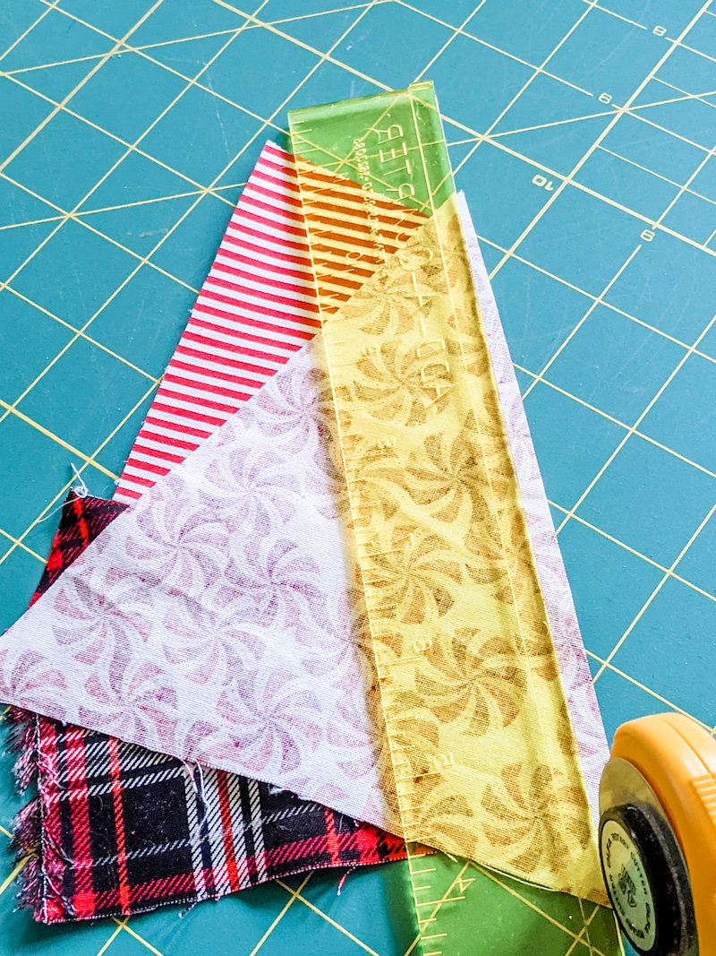 A yellow ruler measuring a straight line across three scraps of fabric.