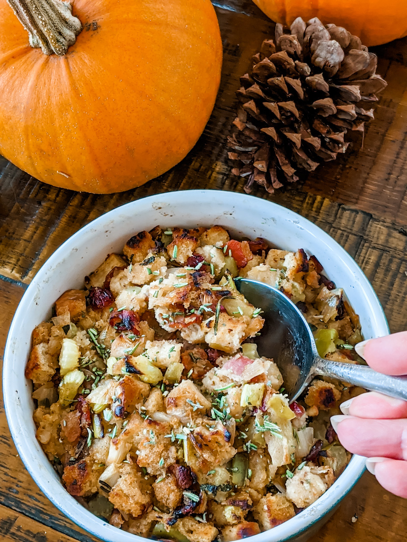 The completed turkey dressing in a bowl with a serving spoon being dipped into it.