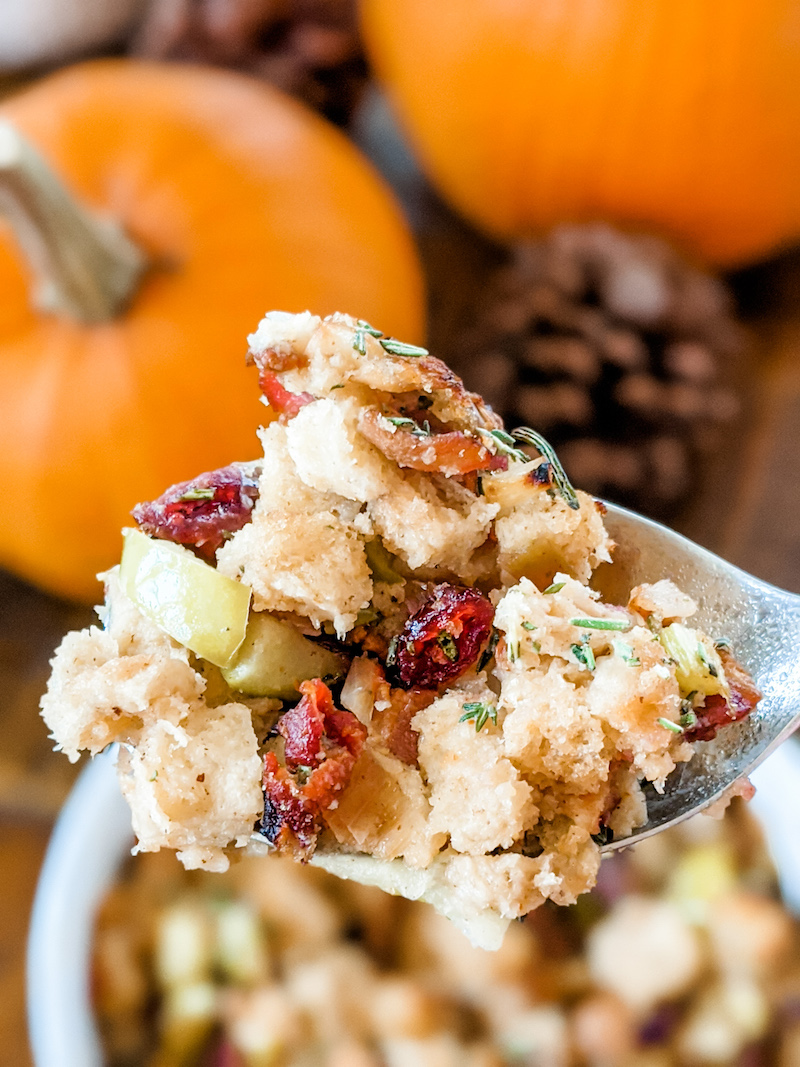 A spoonful of Marie's Flavorful and Moist Turkey Dressing, with a pumpkin and pine cone in the background