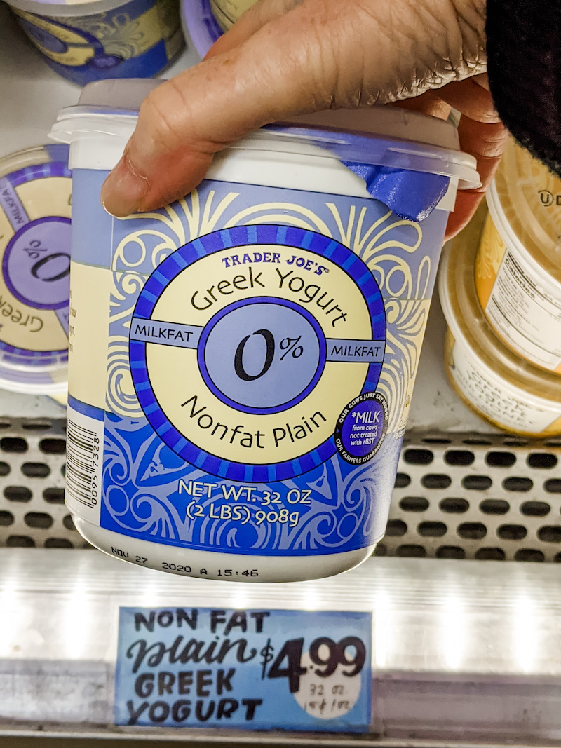 Marie's hand holding a container of Greek yogurt