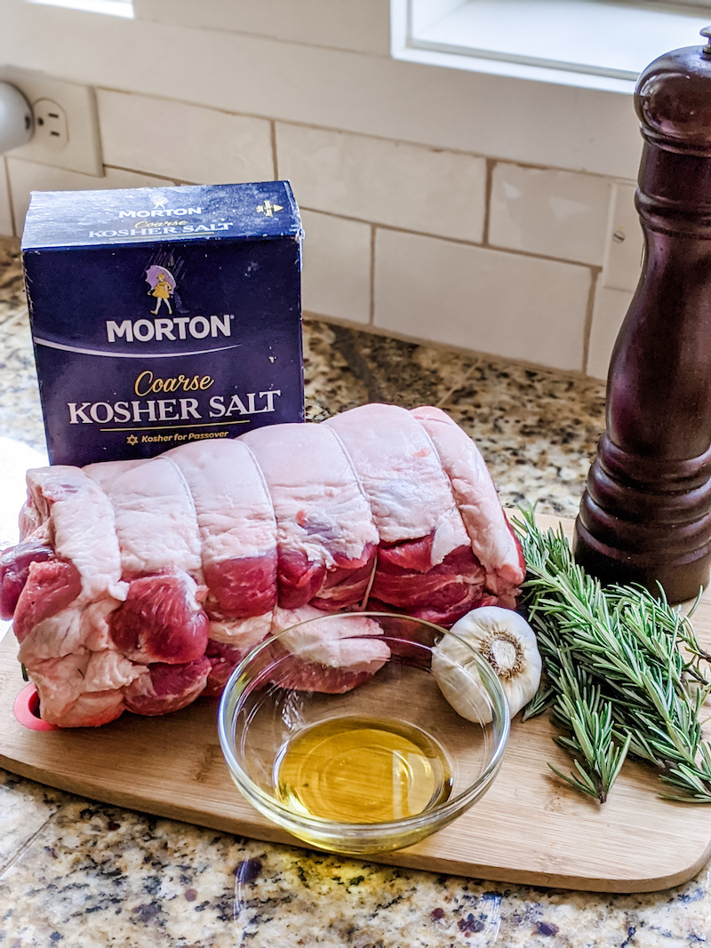 The uncooked boston pork butt roast sitting on a utting board alongside the ingredients for the marinade 