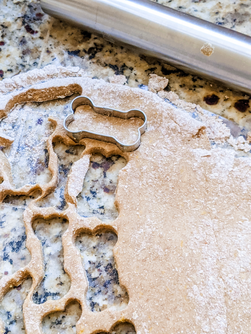 The rolled out dough with several cut-outs from the cookie cutter already in it.