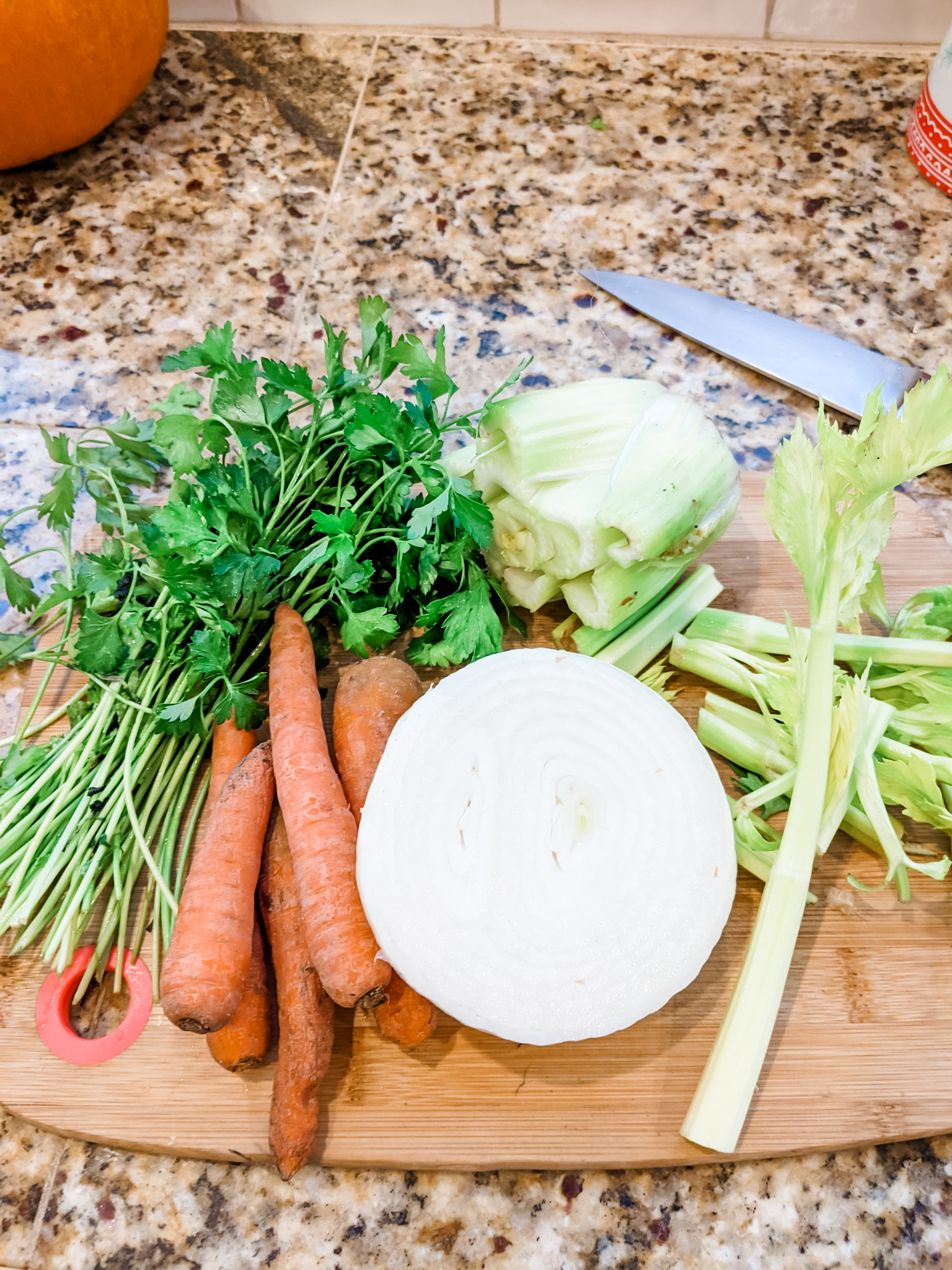 The veggies and scraps for the stock sitting on a wooden cutting board