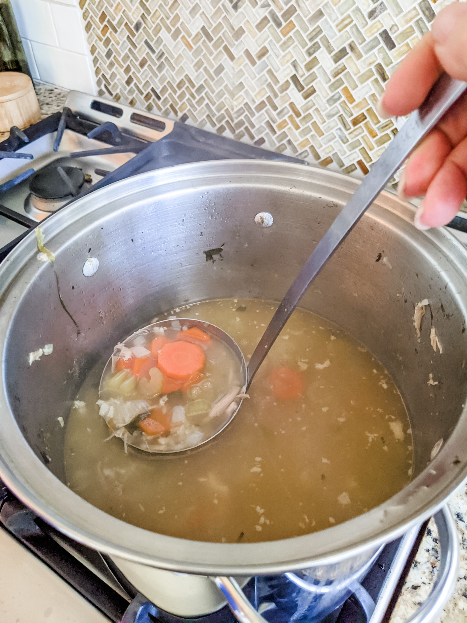 The Leftover Turkey Soup Recipe in the stock pot, with a ladle skimming off some of the fat