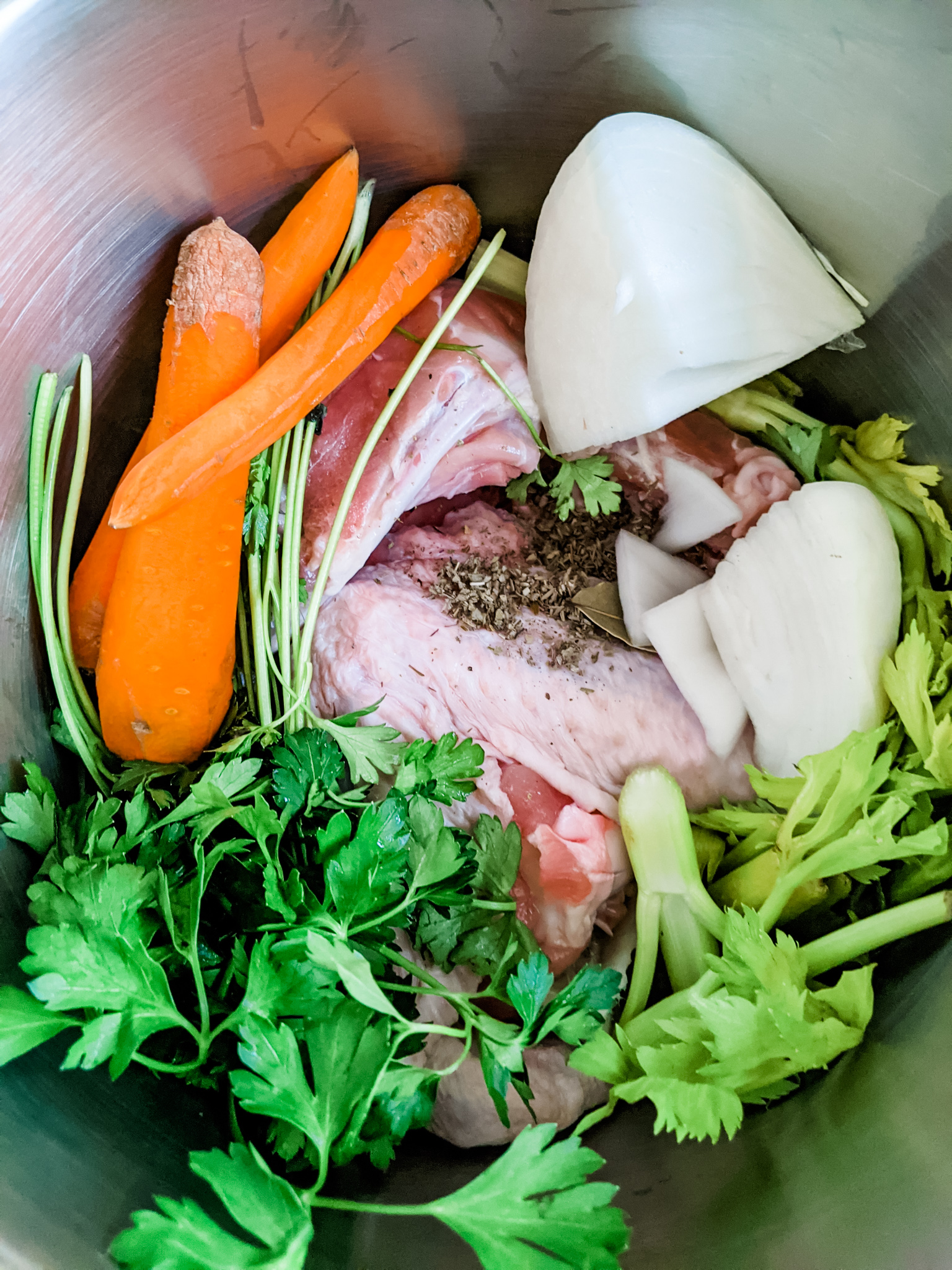 The veggies, scraps, and leftover turkey piece in the metal stock pot