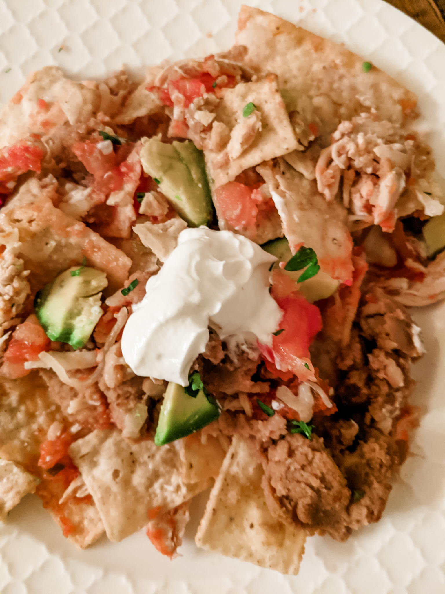 The finished and plated Healthier Chicken Nachos topped with guac and sour cream