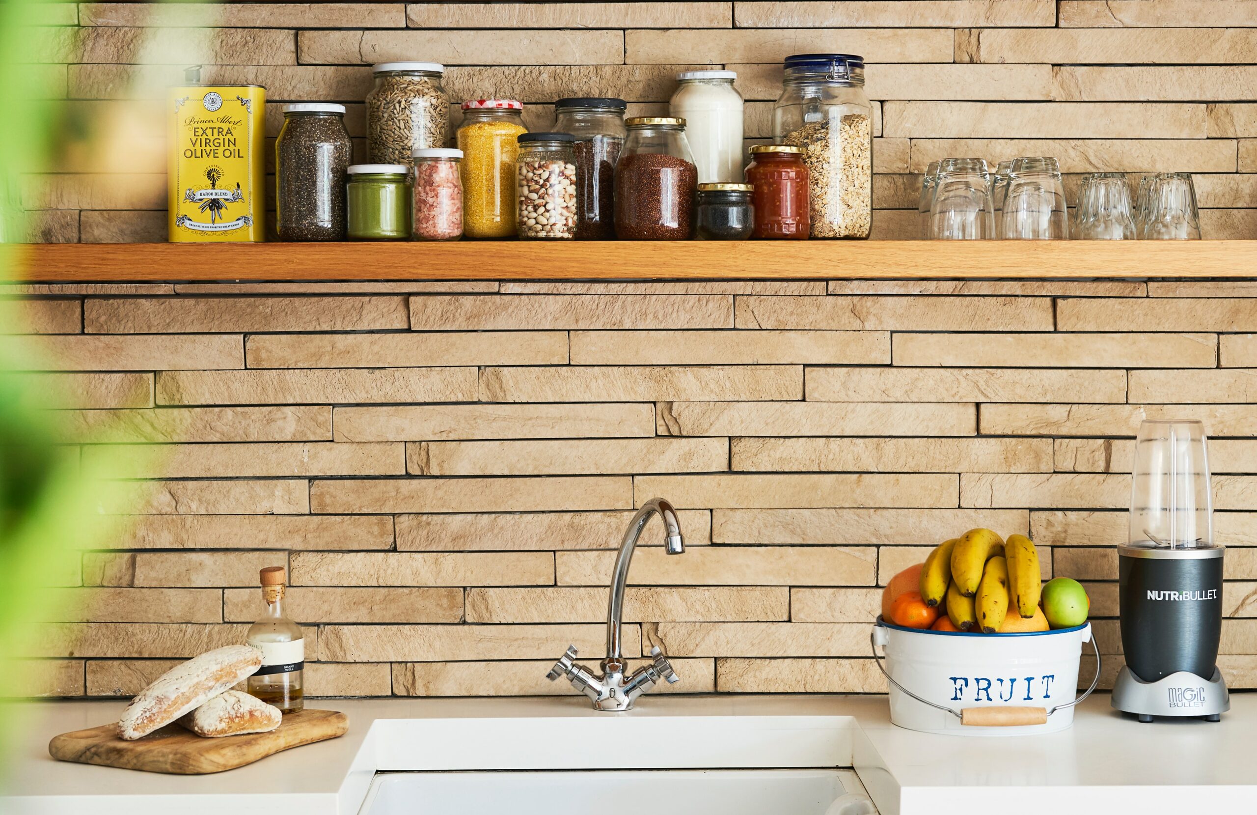 A kitchen sink with a shelf full of spices above it.