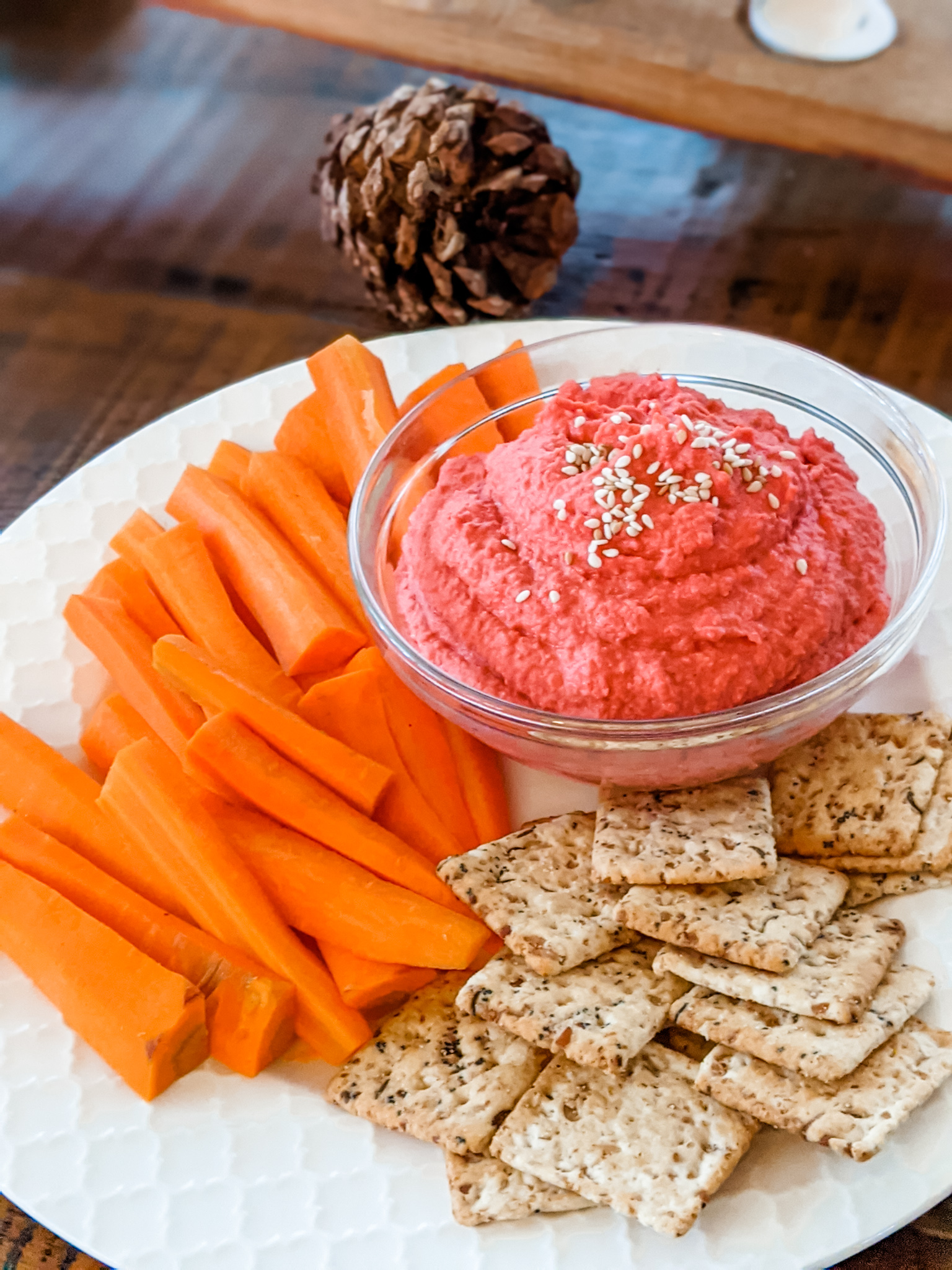 A plate of carrots, hummus, and crackers.