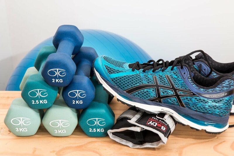 A collection of workout equipment - weights, shoes, ball - all of which are blue