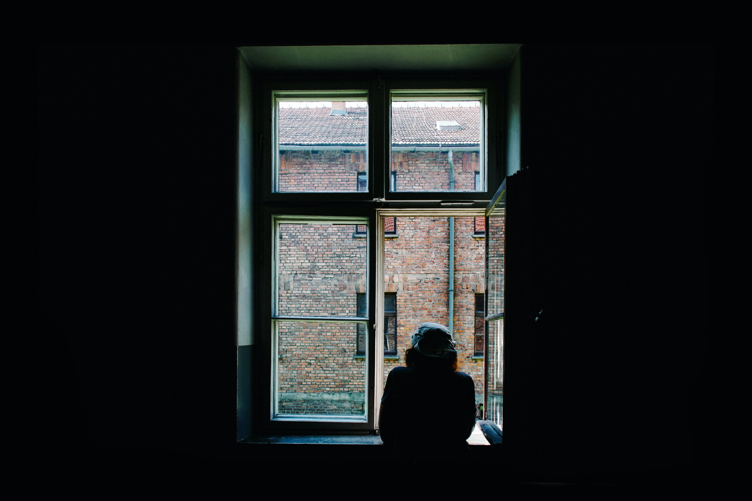 A woman looks out a window, bringing reflections of a different resolution for 2021