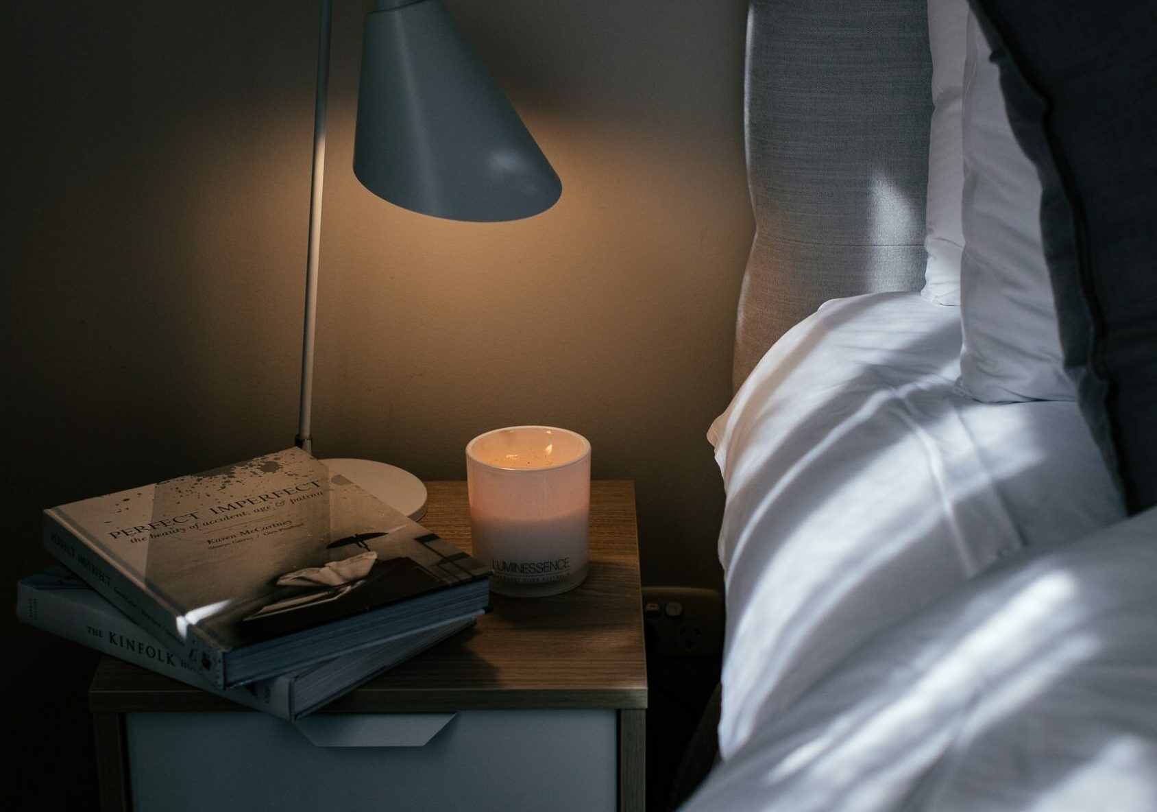 A bedside with diffused soft lighting and candle - a way to treat insomnia naturally
