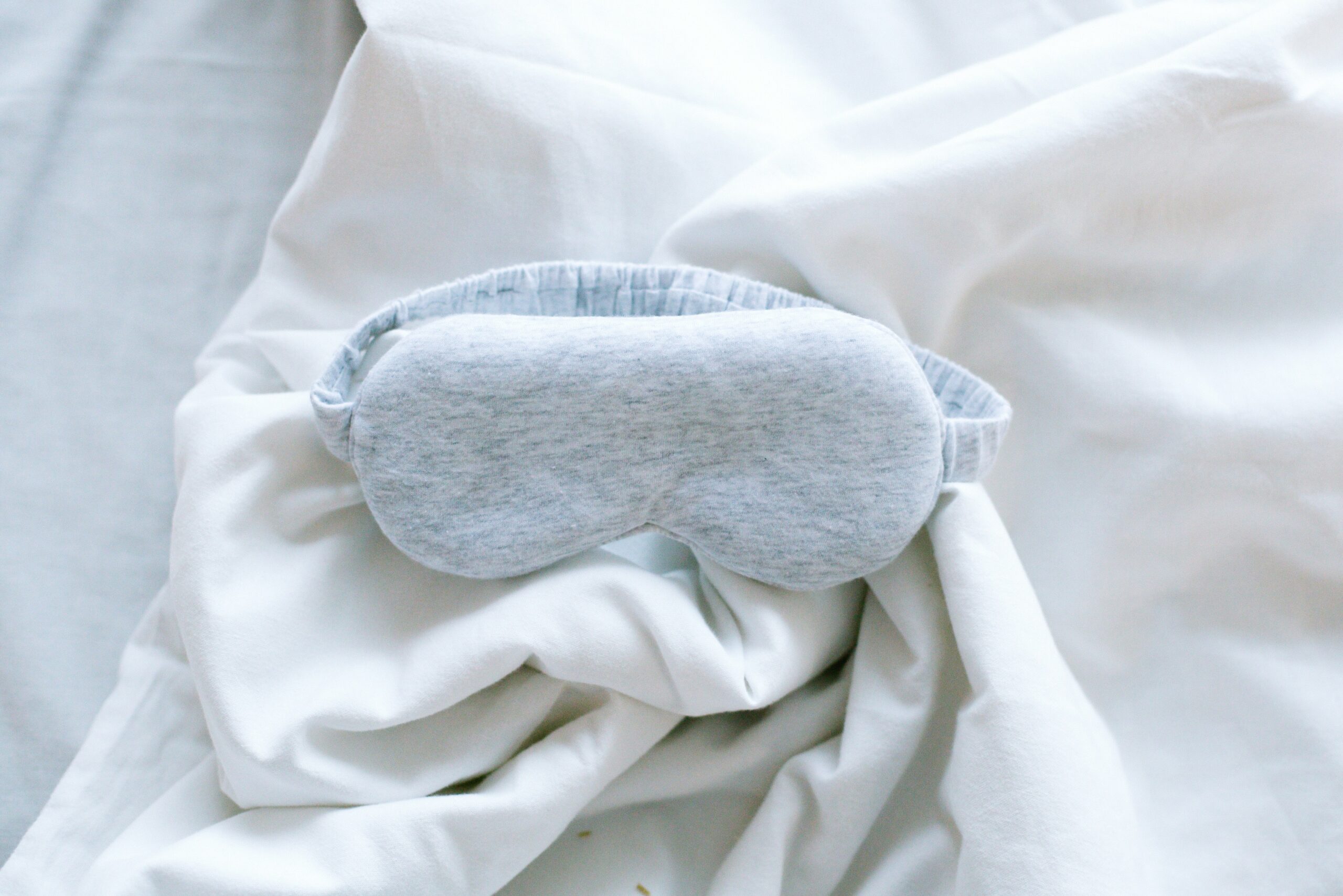 A sleeping mask on top of some sheets.