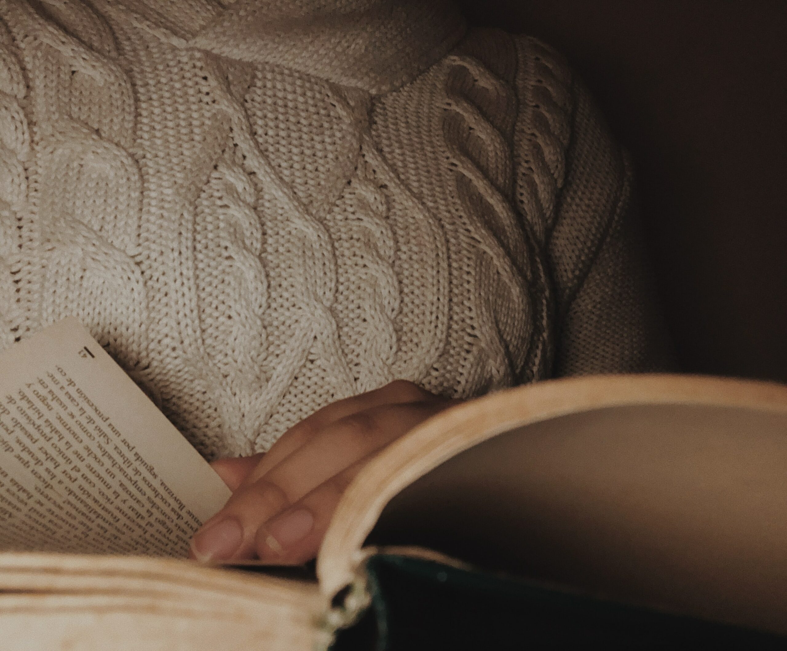 A woman reading a book in dim lighting - taking a break from trying to sleep, a way to treat insomnia naturally