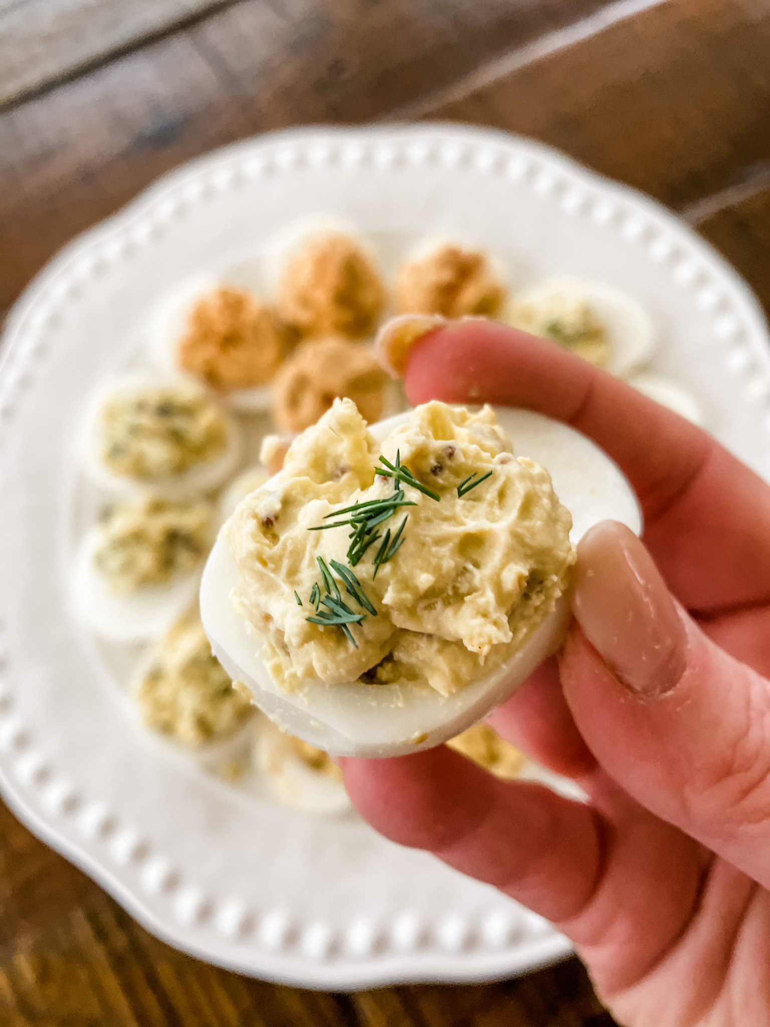 A hand holding up the dill lighter deviled eggs