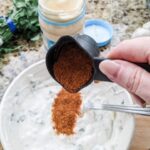 Marie dropping some of the taco seasoning into the Lighter Southwestern Buttermilk Ranch