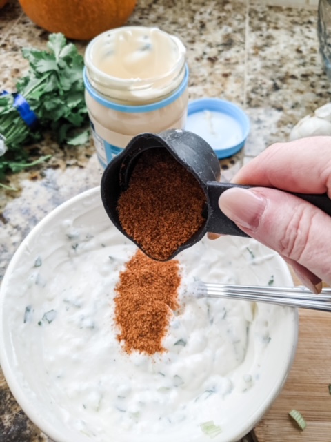 Marie dropping some of the taco seasoning into the Lighter Southwestern Buttermilk Ranch