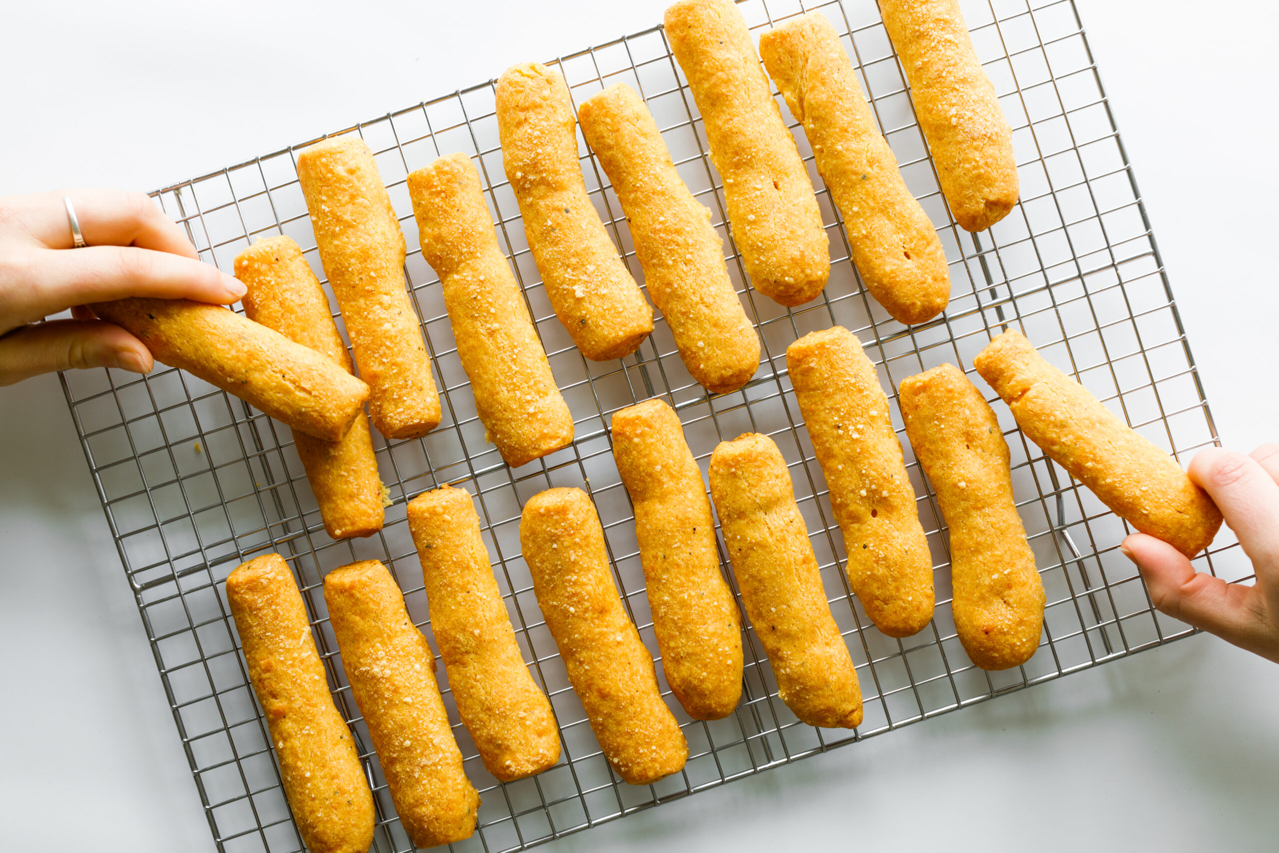 The Parmesan and Sharp Cheddar Cheese Straws, with two hands picking some off