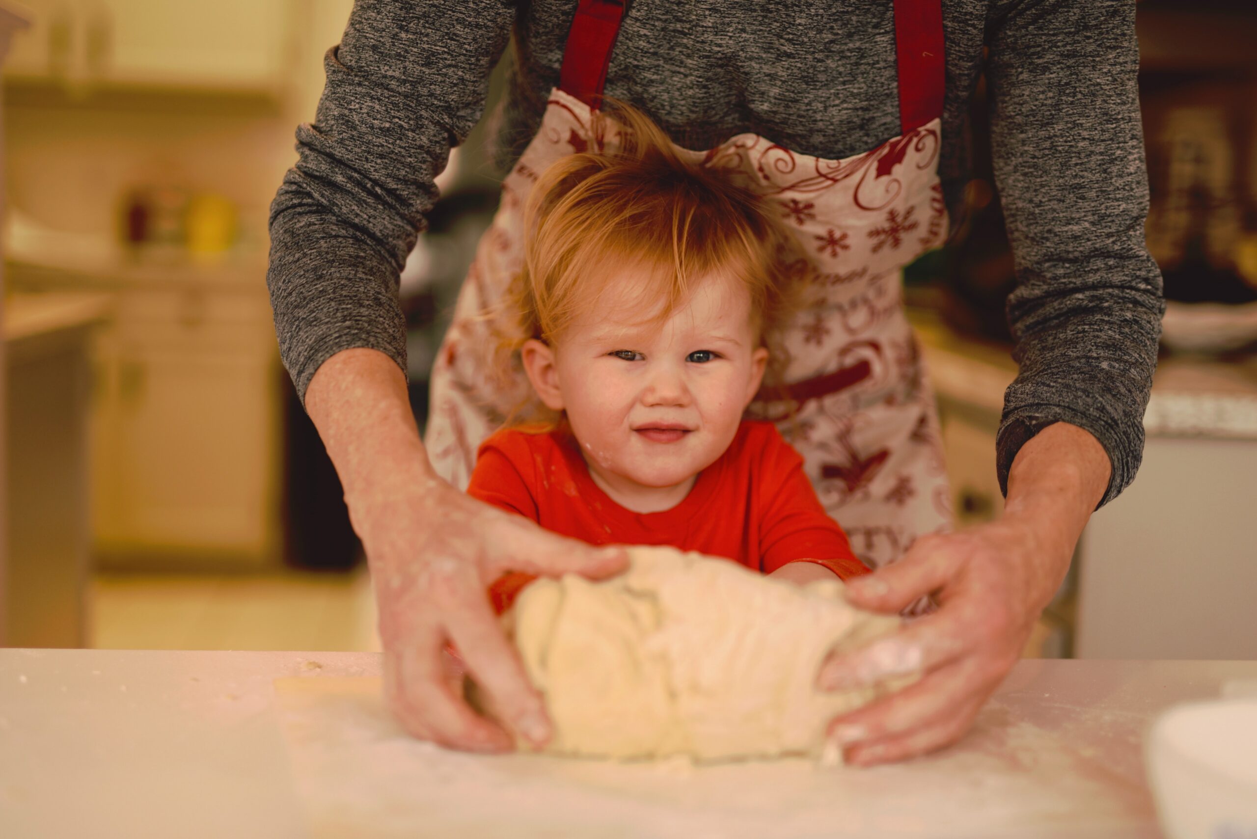 A woman kneads bread with a toddler.