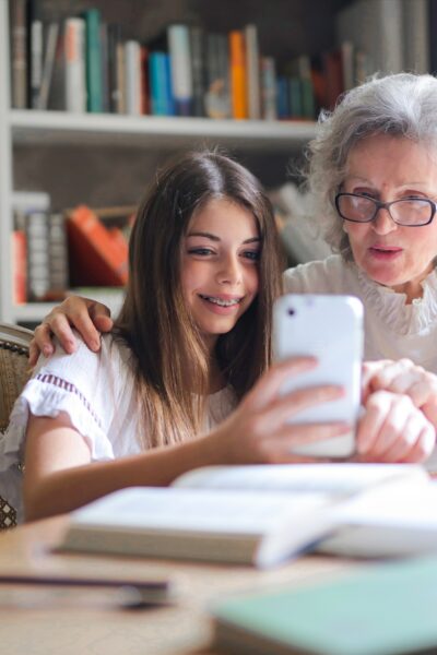 A woman and her granddaughter look at a phone together