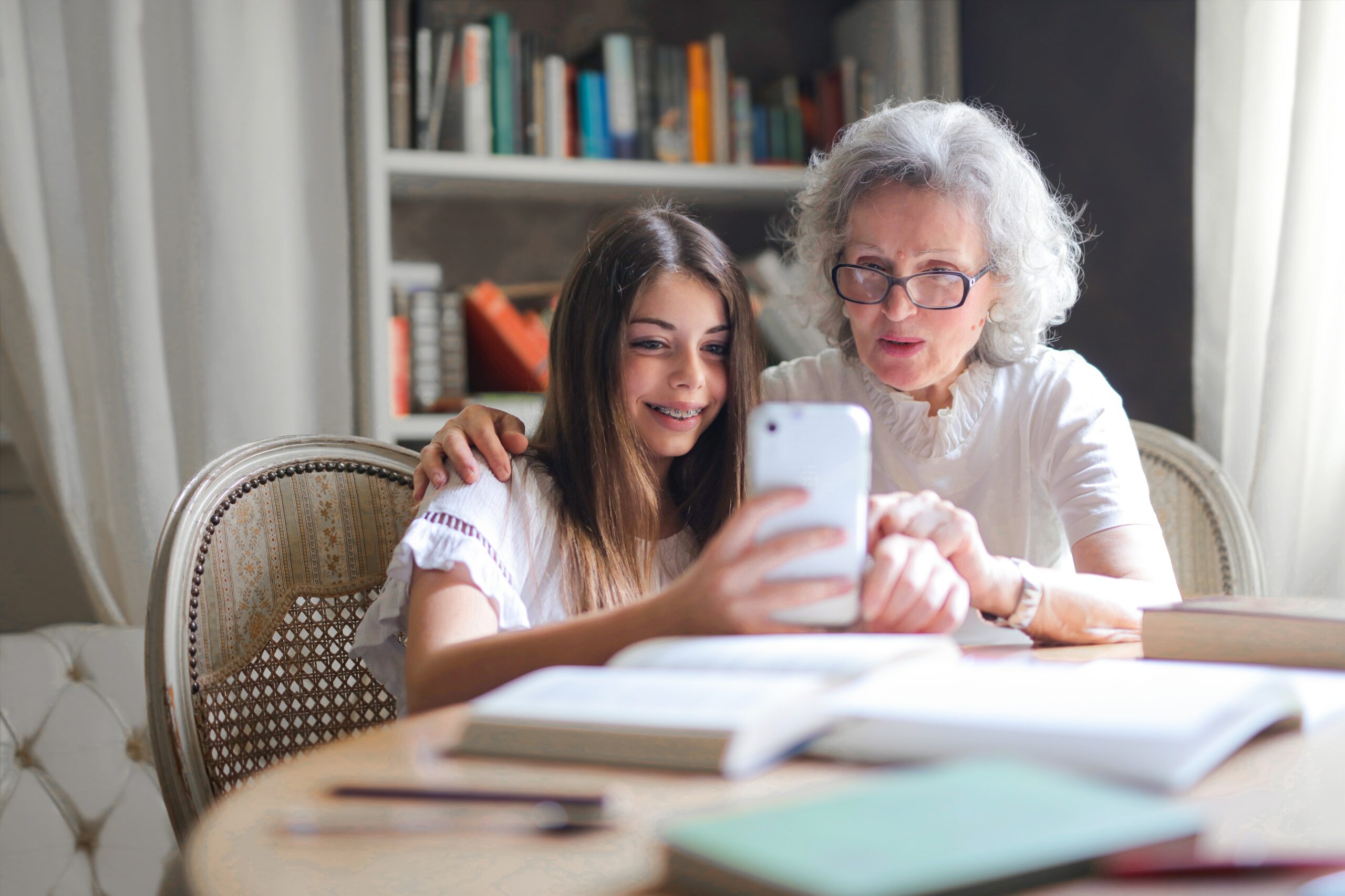 A woman and her granddaughter look at a phone together - one of the most well-known ways of of keeping in touch with kids 