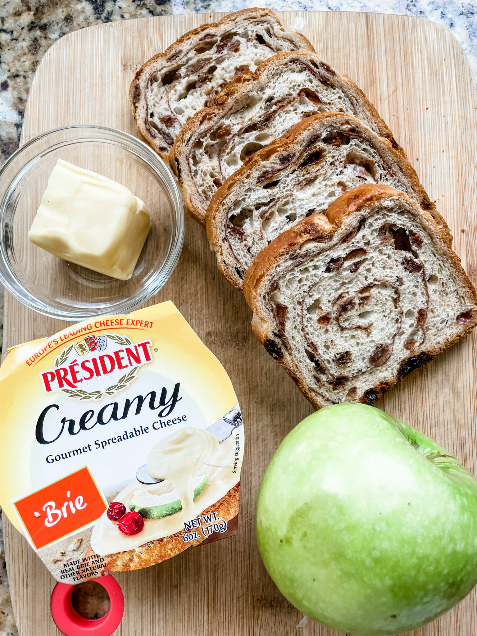 The four ingredients for Grilled Apple and Brie Cheese Sandwiches on a wooden cutting board