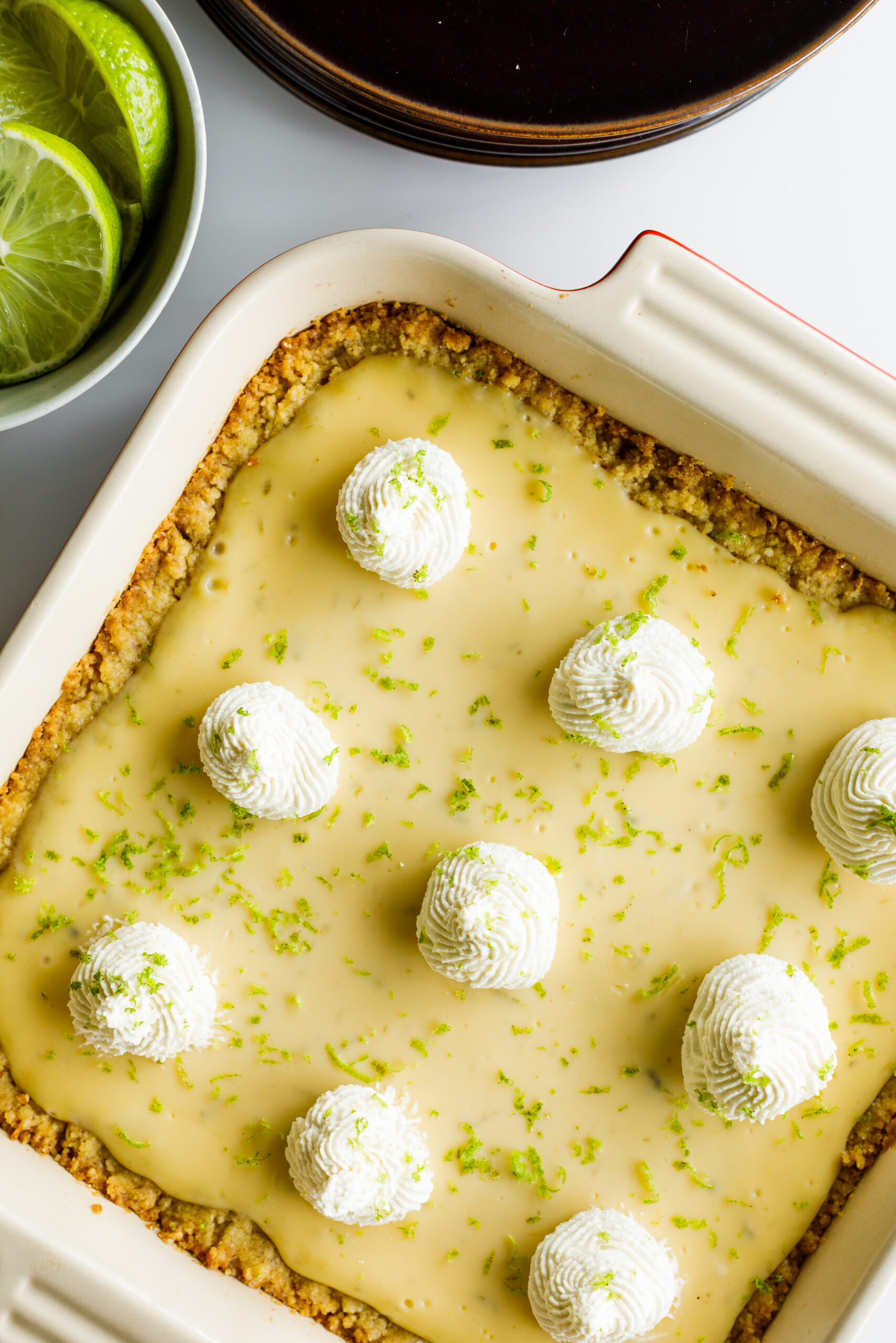 The finished key lime pie bars with some sliced key limes next to them