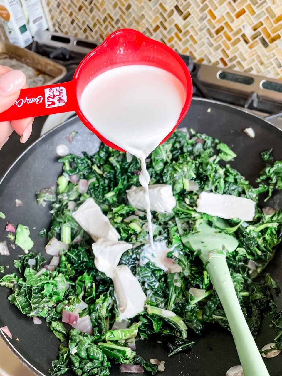 Marie pouring in the half and half for the Creamed Kale Casserole with Parmesan